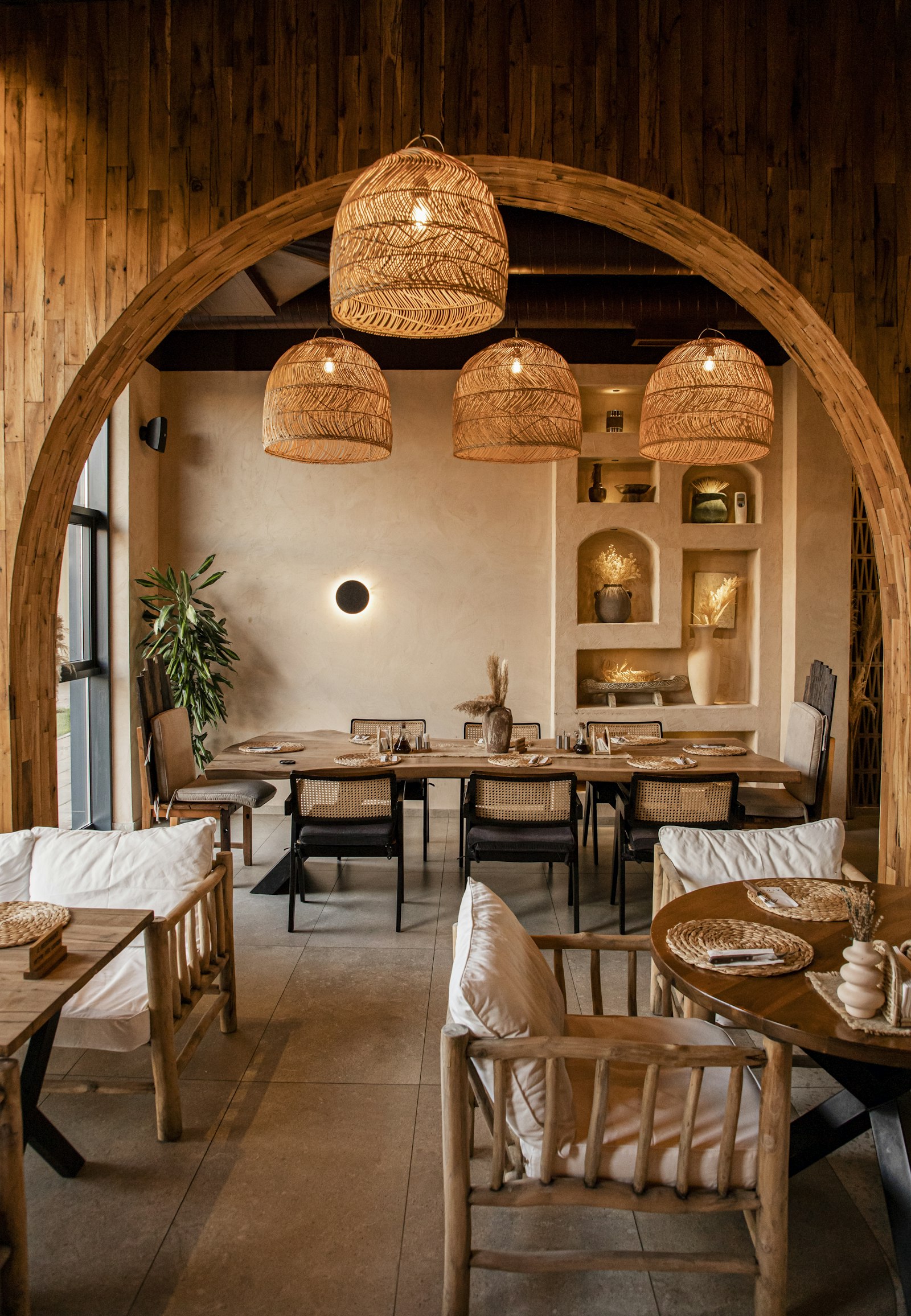 Dining area with natural wood tables and woven pendant lights